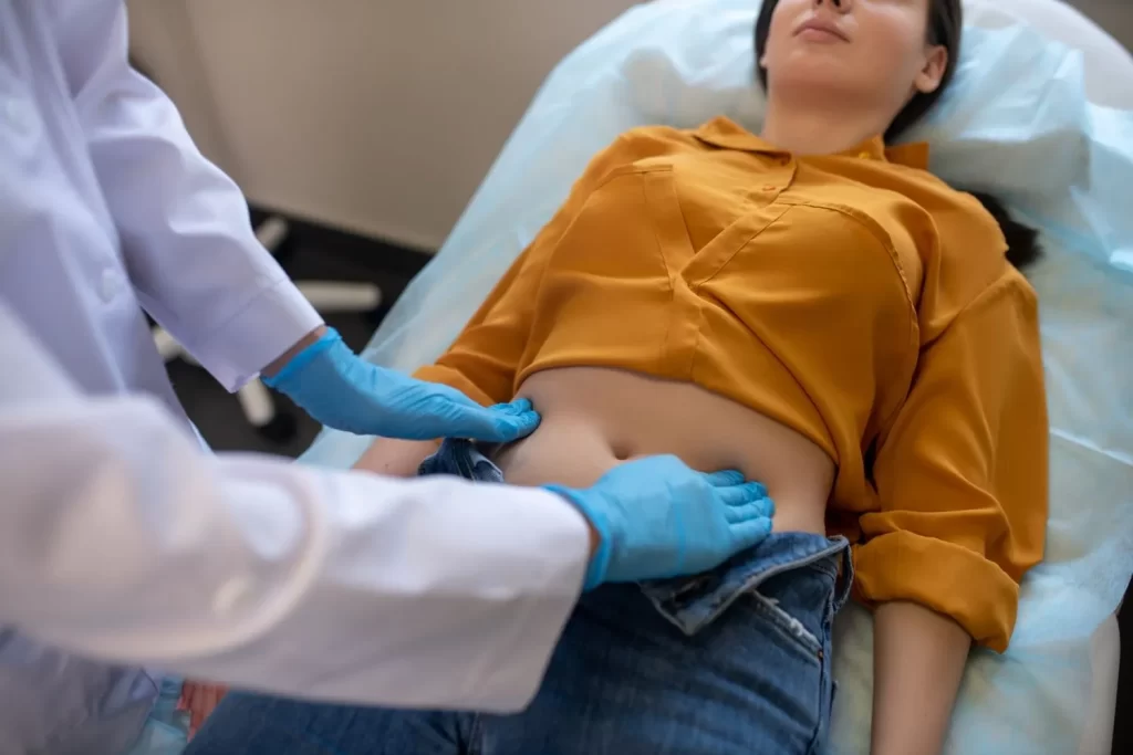 Doctor performing abdominal examination on a woman during gastroenterology consultation