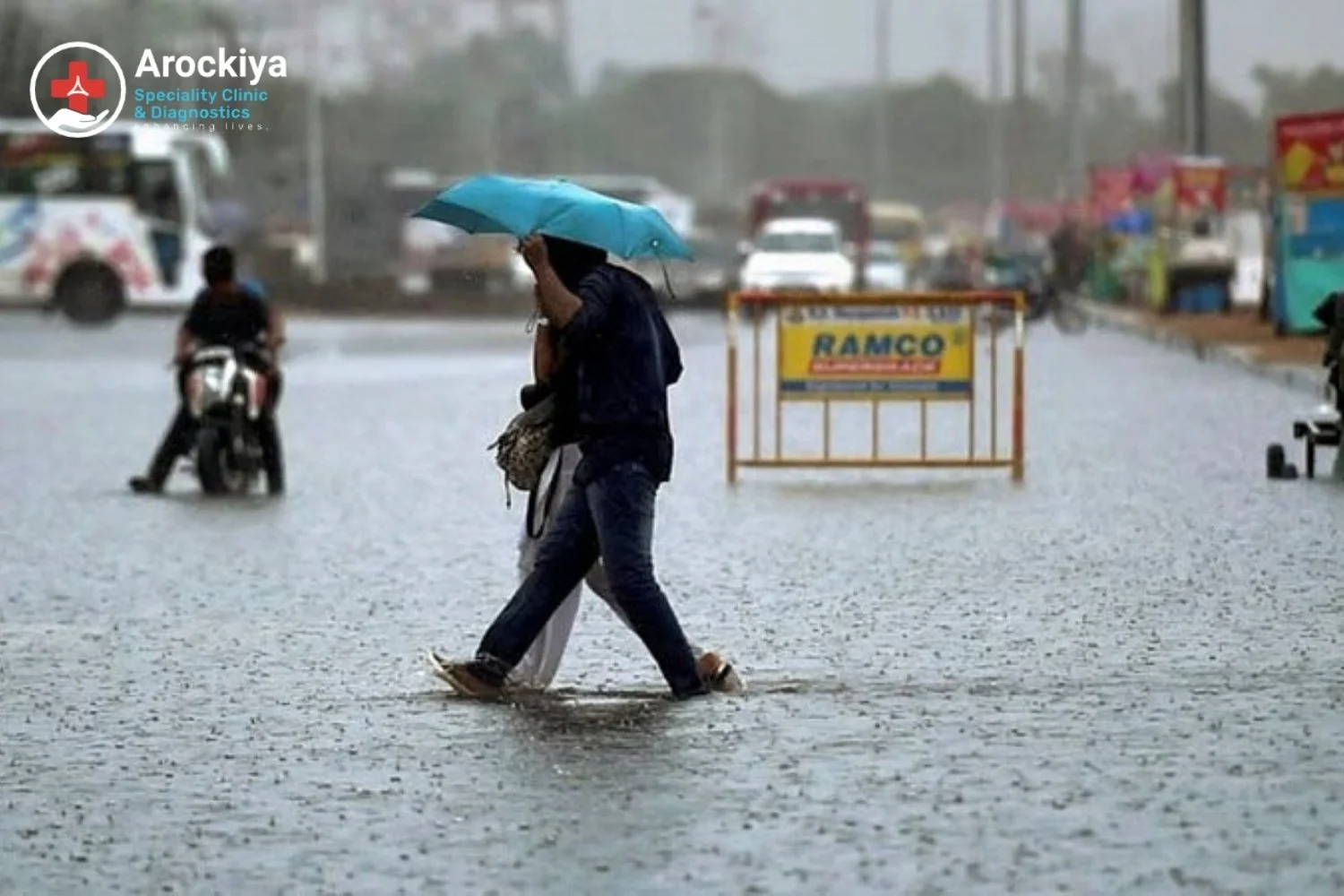 People walking with an umbrella on a flooded Chennai street during monsoon season – highlighting health and immunity care tips by Arockiya Clinic